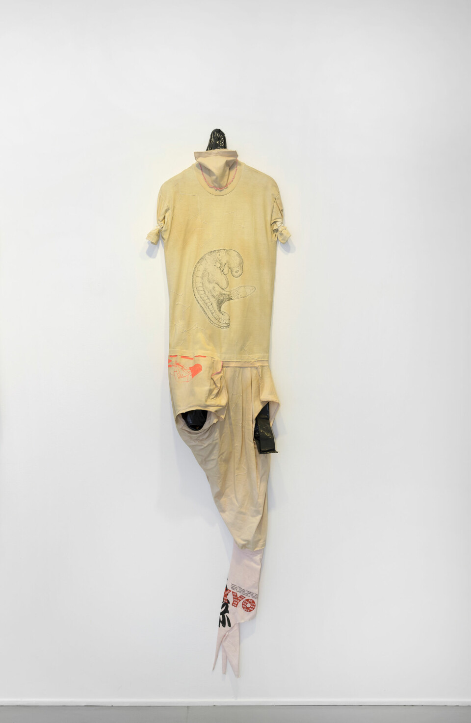 Leif Holmstrand, Costume for a New Tail (It’s a Girl) (2015), textile wall sculpture: T-shirt fabric, print depicting human fetus plus snake head, garbage bag plastic, pearls et cetera. Foto: Øystein Thorvaldsen