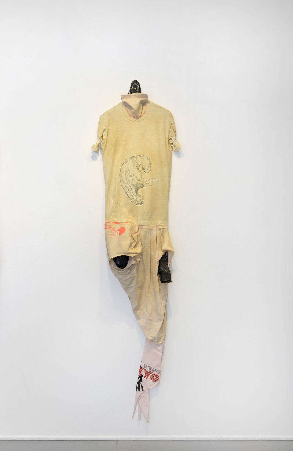 Leif Holmstrand, Costume for a New Tail (It’s a Girl) (2015), textile wall sculpture: T-shirt fabric, print depicting human fetus plus snake head, garbage bag plastic, pearls et cetera. Foto: Øystein Thorvaldsen