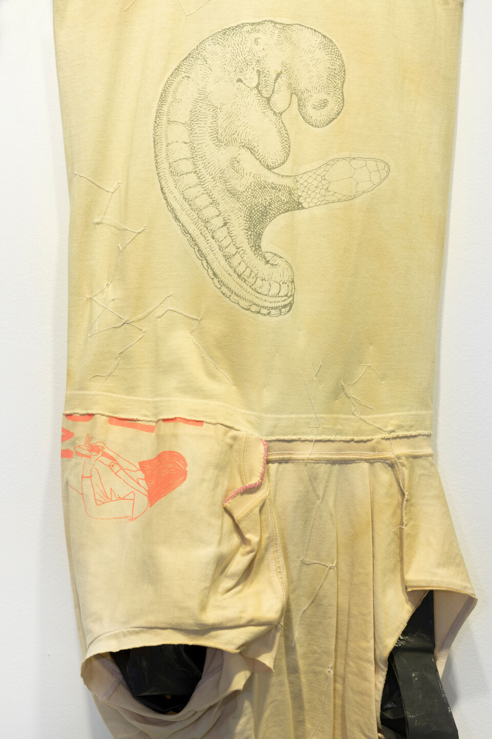 Detalj av Leif Holmstrand, Costume for a New Tail (It’s a Girl) (2015), textile wall sculpture: T-shirt fabric, print depicting human fetus plus snake head, garbage bag plastic, pearls et cetera. Foto: Øyvind Thorvaldsen Detalj av Leif Holmstrand, Costume for a New Tail (It’s a Girl) (2015), textile wall sculpture: T-shirt fabric, print depicting human fetus plus snake head, garbage bag plastic, pearls et cetera. Foto: Øyvind Thorvaldsen